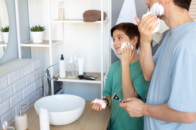 Side view father and kid applying shaving cream