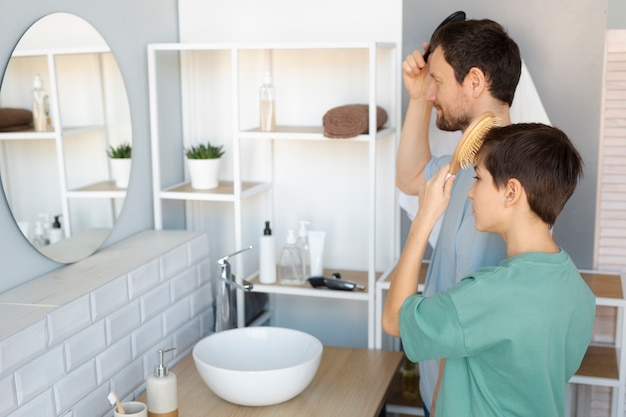 Free photo side view father and kid brushing hair