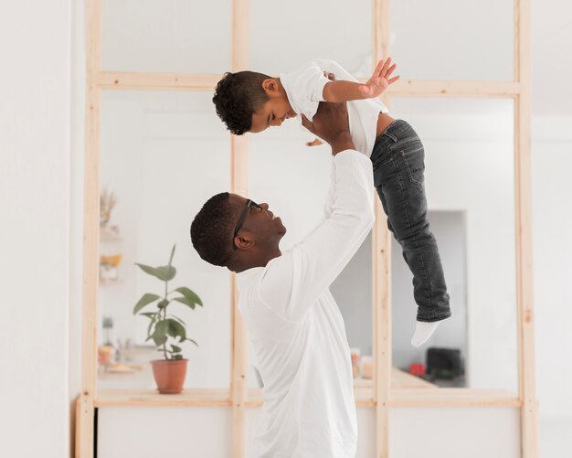 Side view father playing with his son indoors