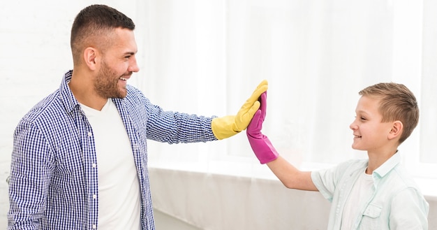 Side view of father and son high-fiving each other while cleaning