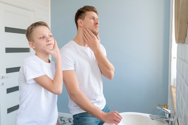 Side view father and son looking in the mirror