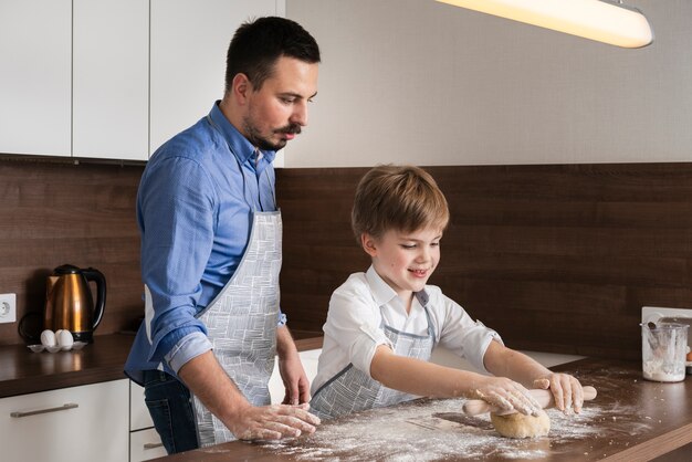 Side view father and son rolling dough