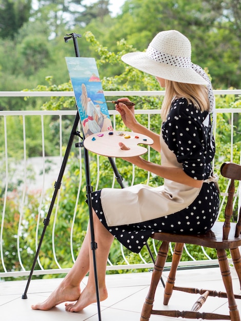 Side view of female artist painting outdoors