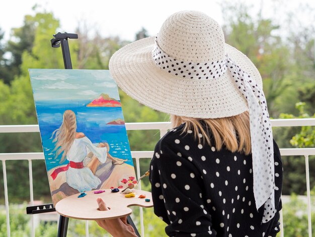 Side view of female artist painting with palette