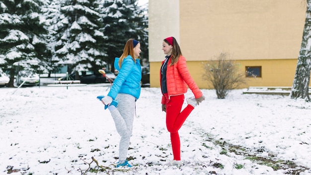 Side view of female athlete stretching her leg in winter