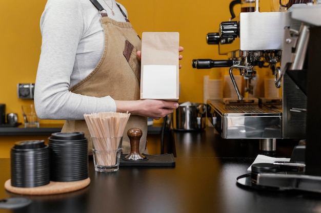 Vista laterale del barista femminile che macina i chicchi di caffè