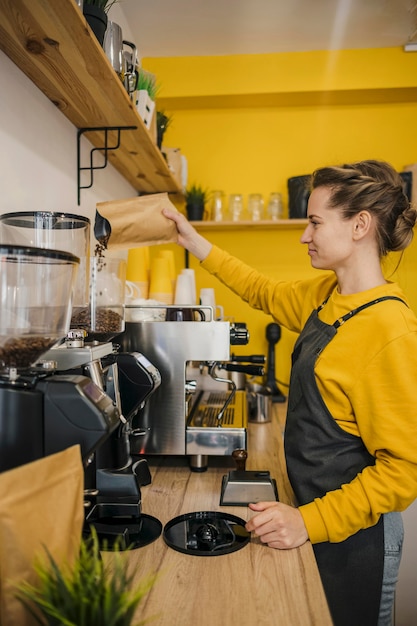 Side view of female barista grinding coffee