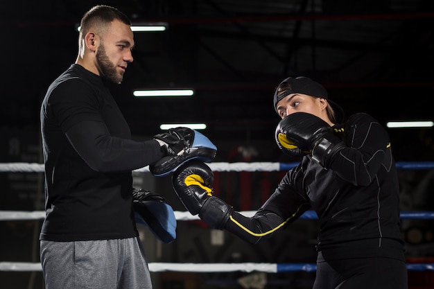 Free photo side view of female boxer practicing in the ring