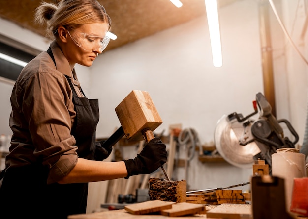 Side view of female carpenter sculpting wood in the studio