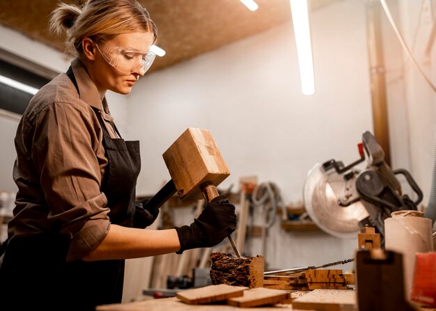 Side view of female carpenter sculpting wood in the studio