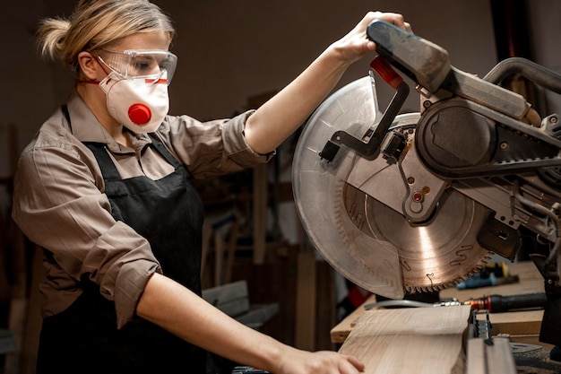 Женщина-плотник с помощью круглой пилы, вид сбоку