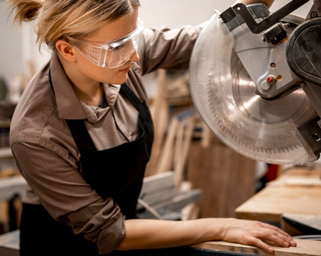 Side view of female carpenter with tool and safety glasses