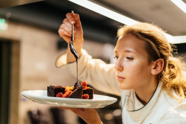 Side view of female chef pouring sauce over dish