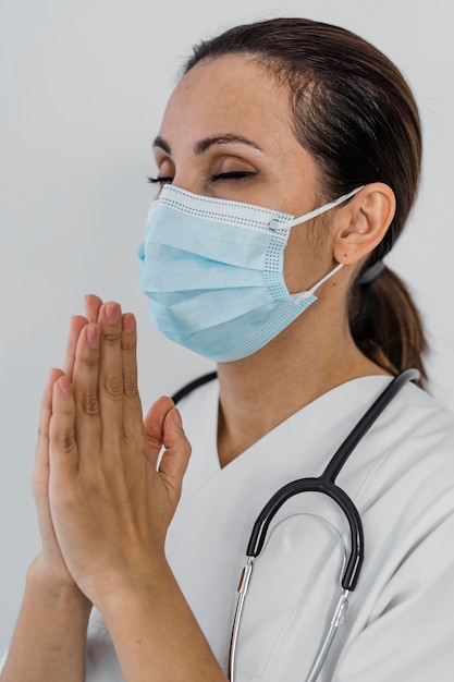 Женщина-врач молится, вид сбоку