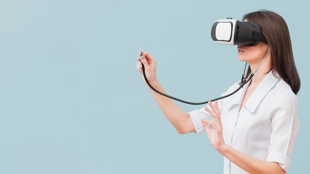 Взгляд со стороны женского доктора используя стетоскоп и шлемофон виртуальной реальности