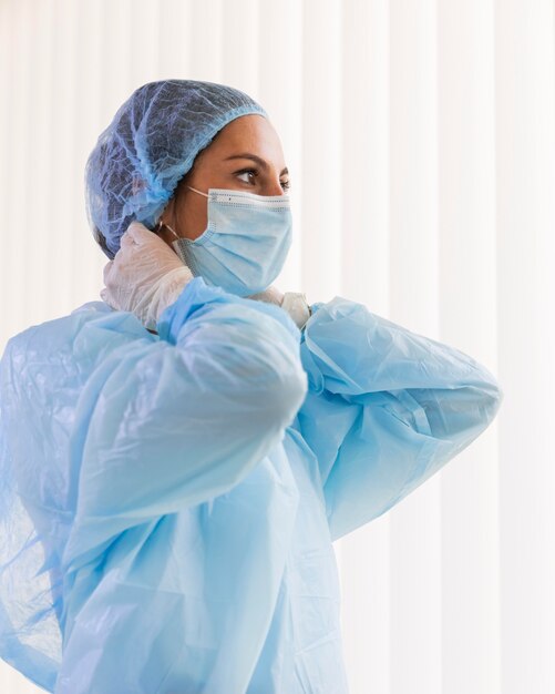 Side view female doctor wearing pandemic equipment