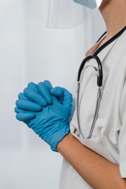 Side view of female doctor with gloves praying