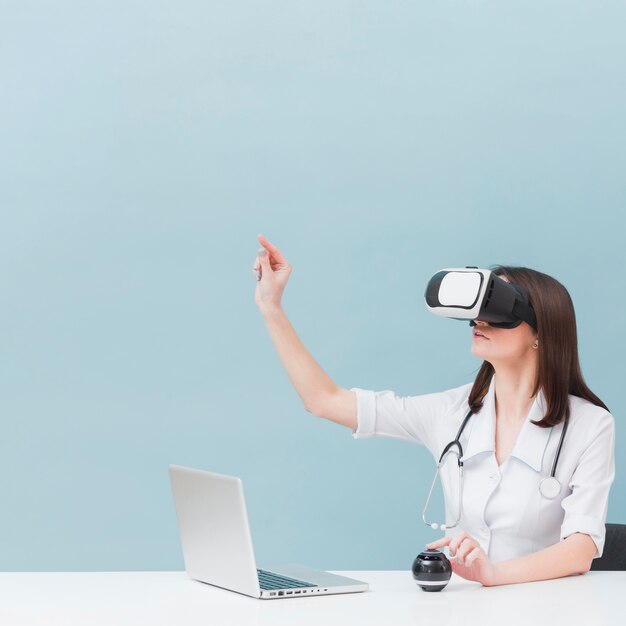 Вид сбоку женщина-врач со стетоскопом, используя гарнитуру виртуальной реальности