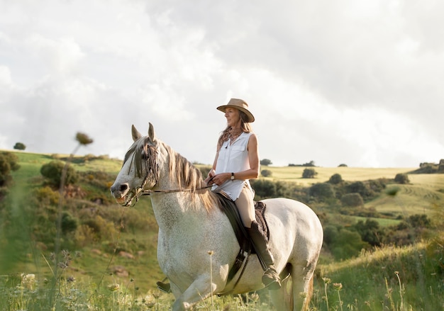 Free photo side view of female farmer horseback riding in nature