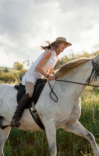 Photo | Side view of female farmer horseback riding outdoors in