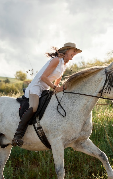 自然の中で屋外に乗っている女性農家の乗馬の側面図