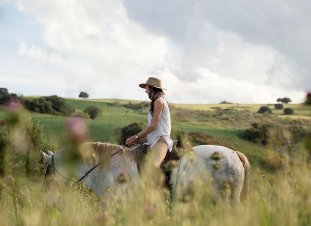 Side view of female farmer horseback riding