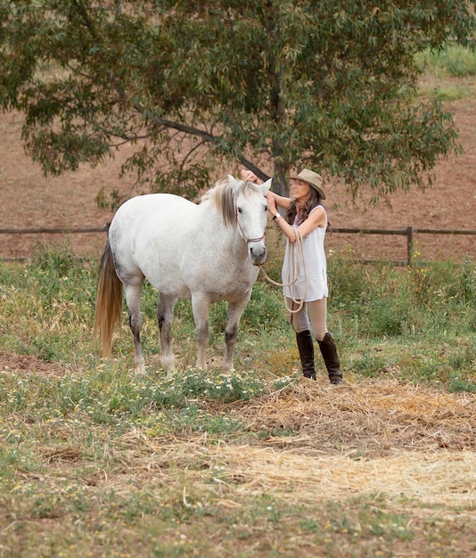 Foto gratuita vista laterale dell'agricoltore femminile che accarezza il suo cavallo