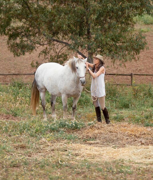 Side view of female farmer petting her horse