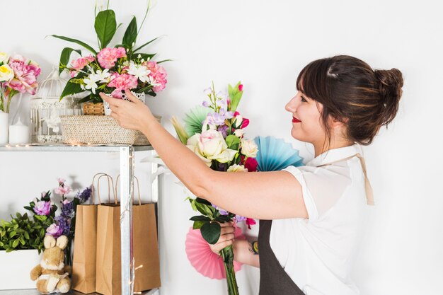 Side view of female florist looking at fresh flowers on shelf