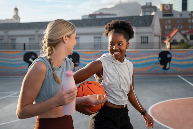 Free photo side view female friends playing basketball