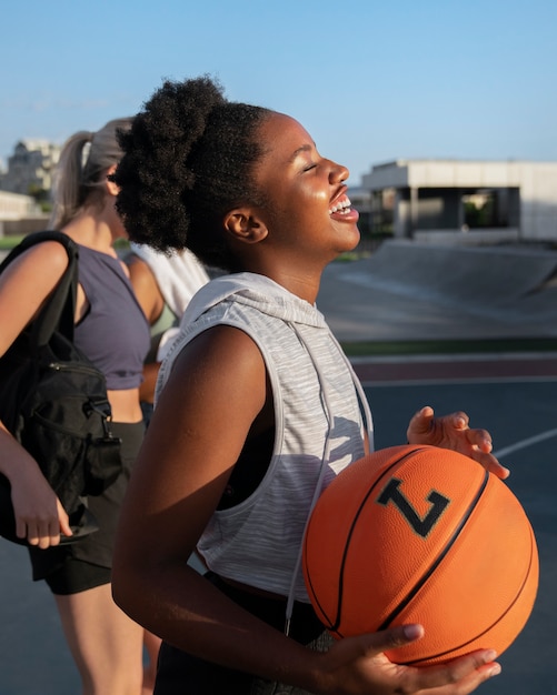 Side view female friends playing basketball