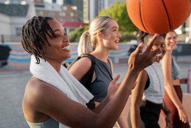 Side view female friends playing basketball