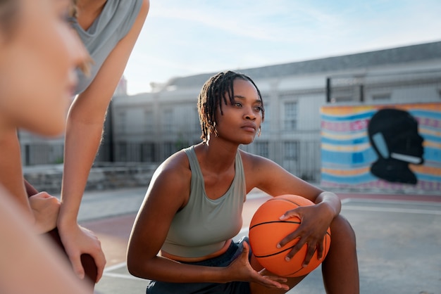 Side view female friends playing basketball