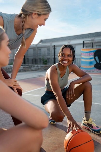 Side view female friends playing basketball
