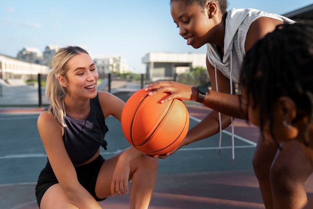 Side view female friends playing basketball