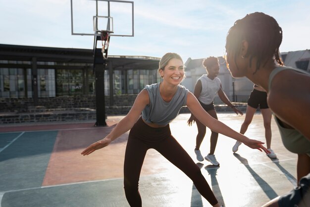 Side view female friends playing basketball
