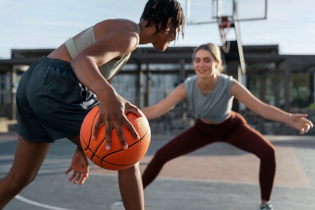 Free photo side view female friends playing basketball