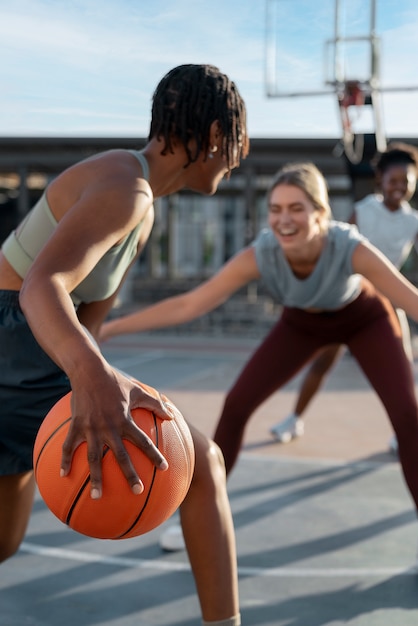 Free photo side view female friends playing basketball