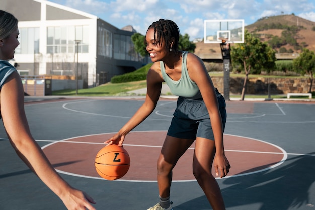 side view female friends playing basketball