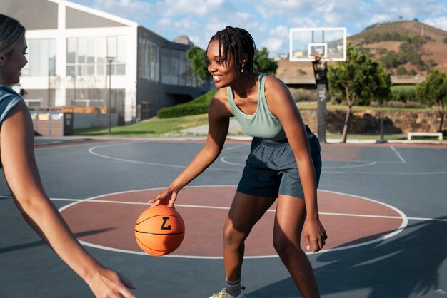 Side view female friends playing basketball