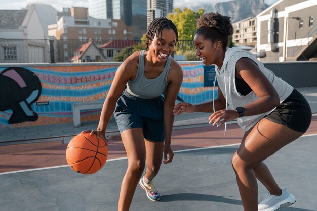 Side view female friends playing basketball