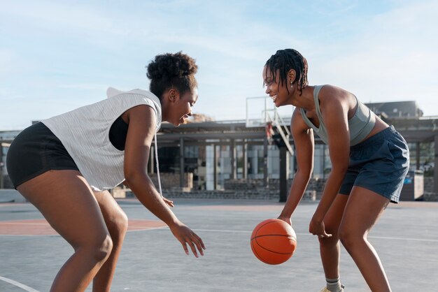 Side view female friends playing basketball