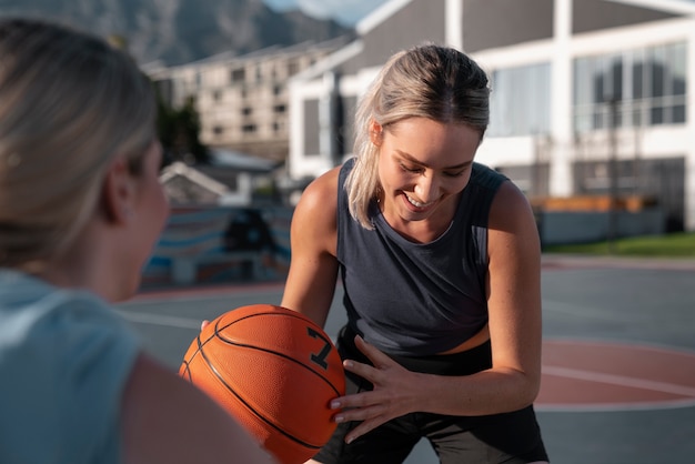 Free photo side view female friends playing basketball