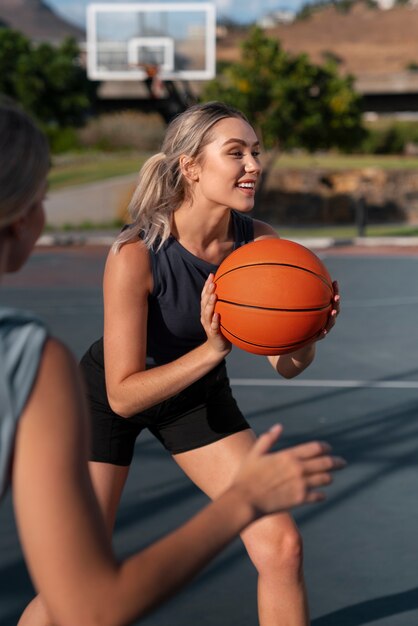 side view female friends playing basketball