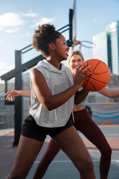 Side view female friends playing basketball