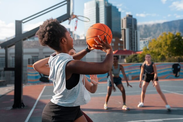 side view female friends playing basketball