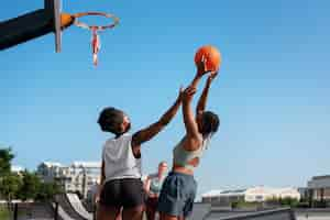 Free photo side view female friends playing basketball