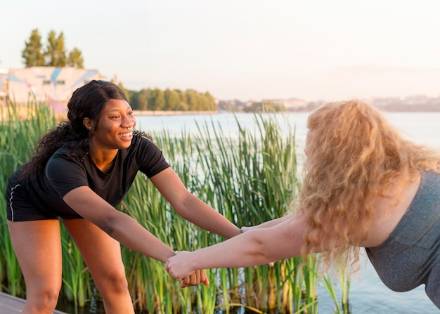 Side view of female friends training together outdoors