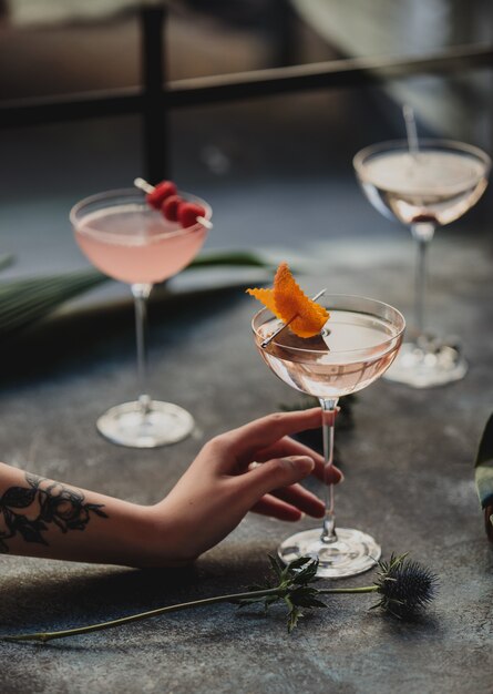 Side view of a female hand holding a glass with pin cocktail