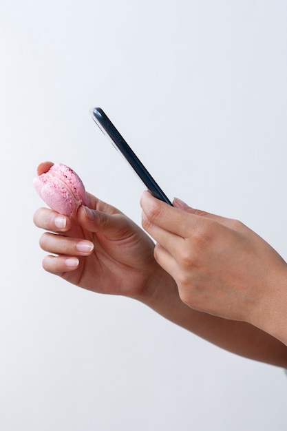 Side view of female hands taking photo of macaron